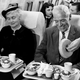 Black and white photo of man and woman receiving elaborate meal on plane